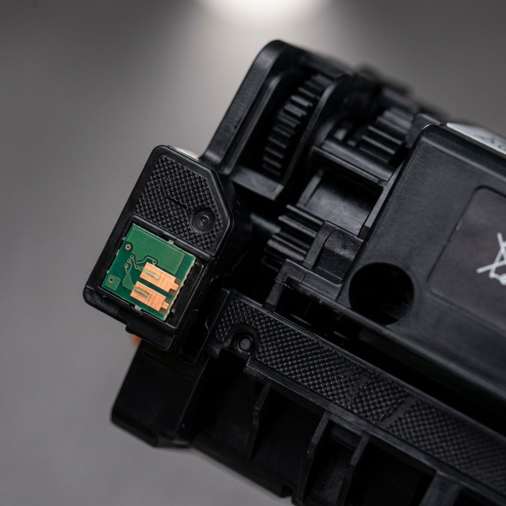 Extreme close-up of the green chip and gold contacts on the black toner cartridge end.