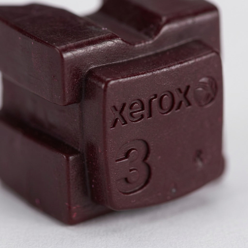 Extreme close-up of Xerox Magenta solid ink stick texture and the embossed 'Xerox 3' logo.