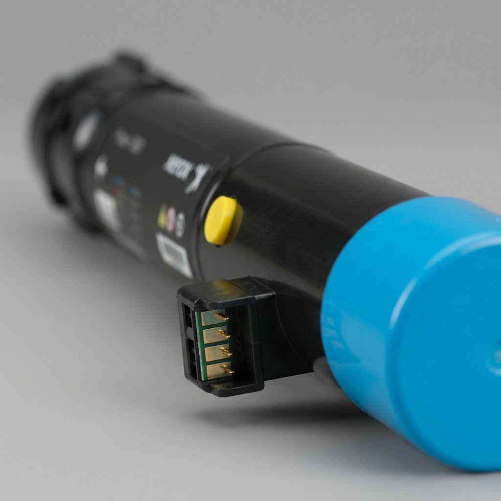 Extreme close-up macro photograph focusing sharply on the yellow release button and complex connection pins at the end of the Xerox 106R01566 toner cartridge. Shallow depth of field blurs surrounding elements.
