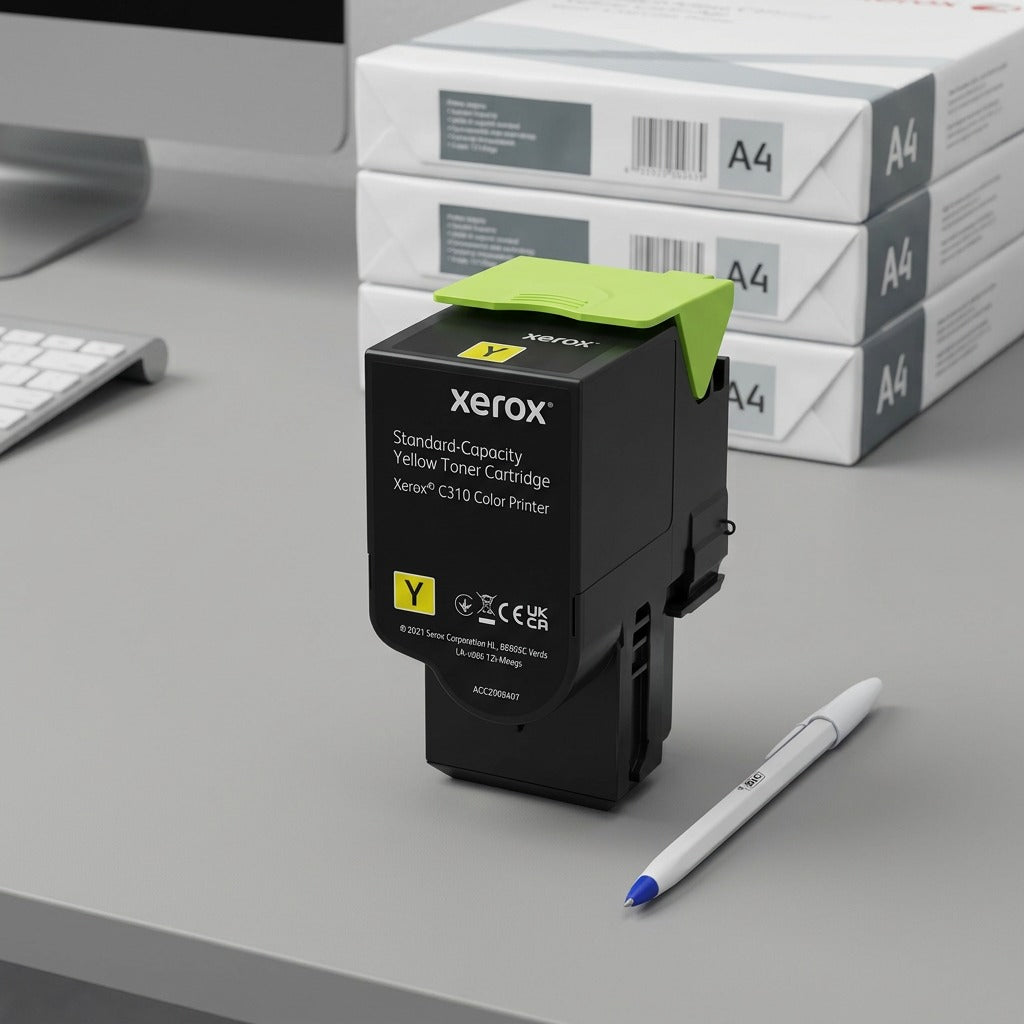 A standard Xerox C310/C315 yellow toner cartridge on a desk, next to a common ballpoint pen for size reference.