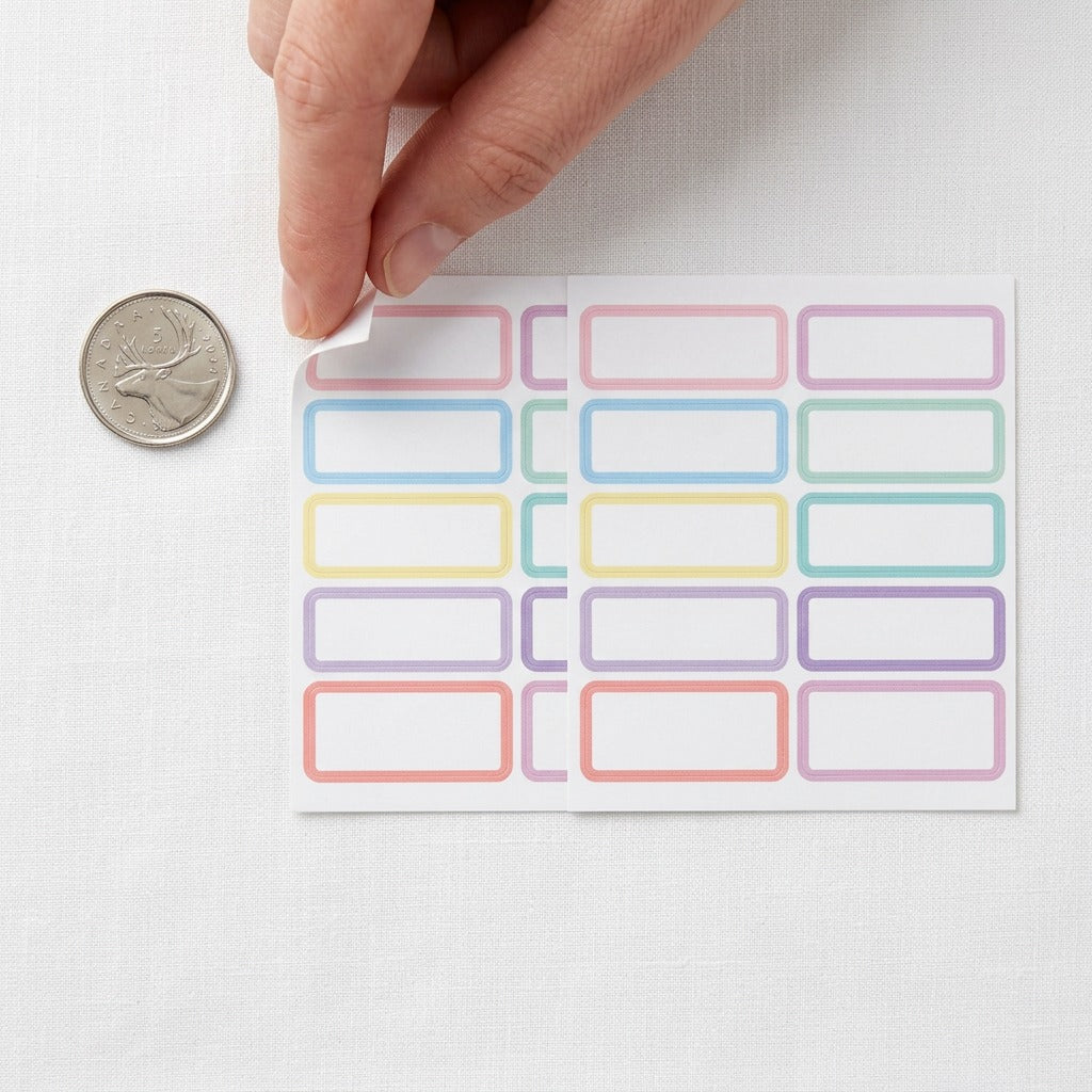 A top-down view of the self-adhesive fabric labels with pastel borders next to a standard coin.