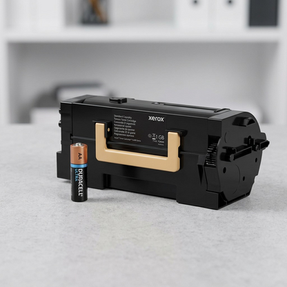 A photorealistic image showing the Xerox black toner cartridge next to a standard AA battery for size reference.